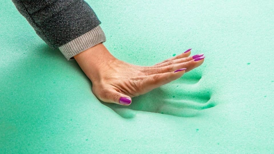 woman placing her hand on a memory foam mattress with a impression of her hand being made